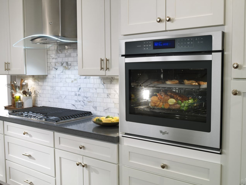 Black glass built-in oven with touch controls in a stylish kitchen. FYIRWA TRADING LTD